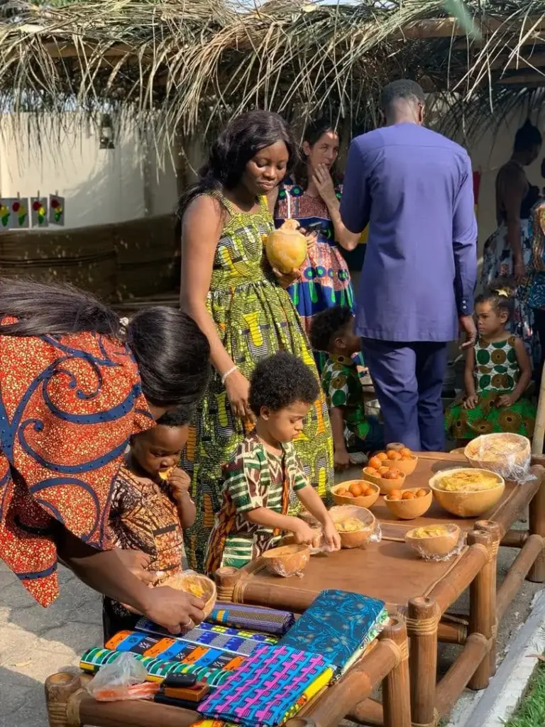 Families in African print outfits sharing Ghanaian food and kente cloth on Culture Day